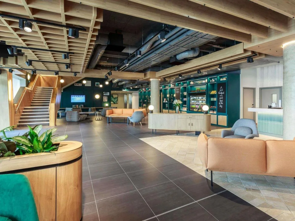 a lobby with furniture and stairs in a building at Novotel Cambridge North in Cambridge