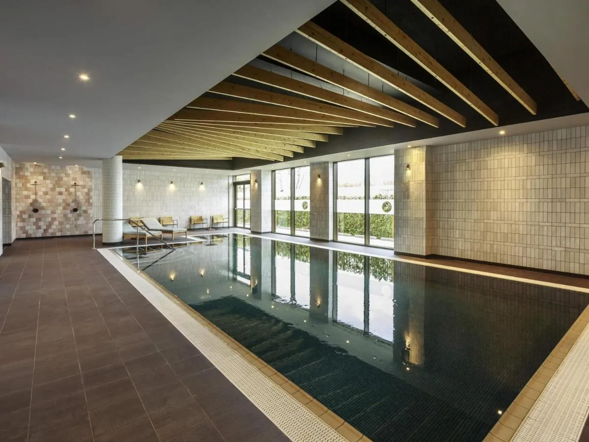 an indoor swimming pool in a building with a swimming pool at Novotel Cambridge North in Cambridge